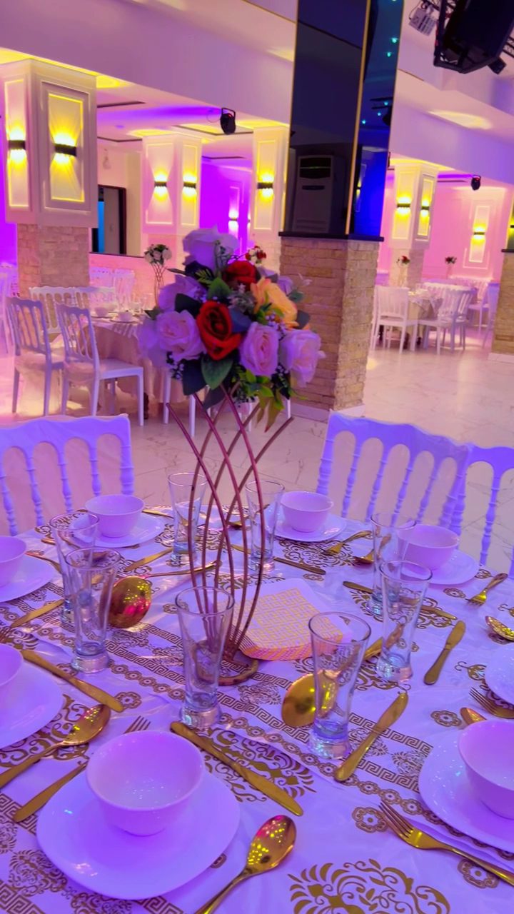 Table dress&eacute;e, vaisselle dor&eacute;e et bouquet de roses sous &eacute;clairage d&rsquo;ambiance